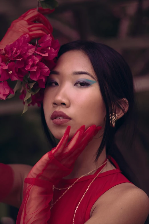 a young woman holds a red flower as she poses