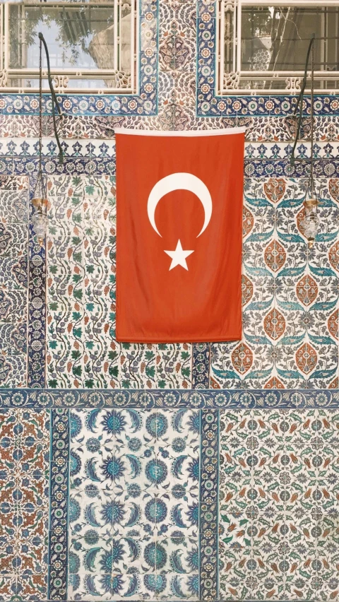 a flag is hanging from a wall of tiles