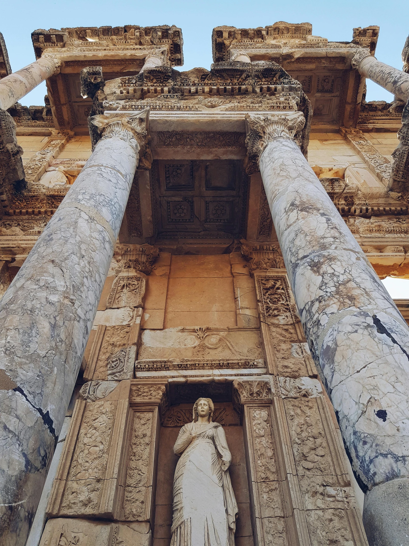 ancient architecture with large columns and statue standing below it