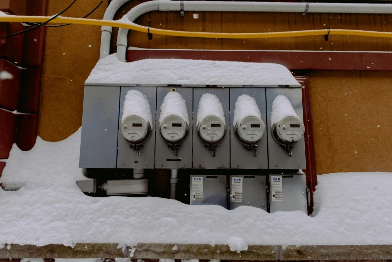 several automatic parking meters in the middle of snow