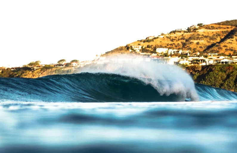 a very large wave breaking over a sandy shore