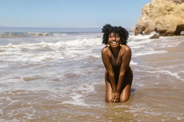 a black woman in a bikini sits on a beach