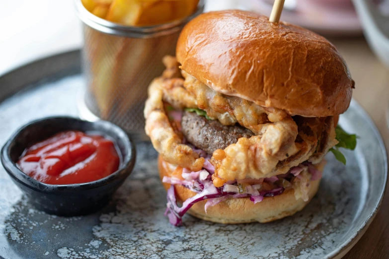 a hamburger on a plate with a glass of ketchup