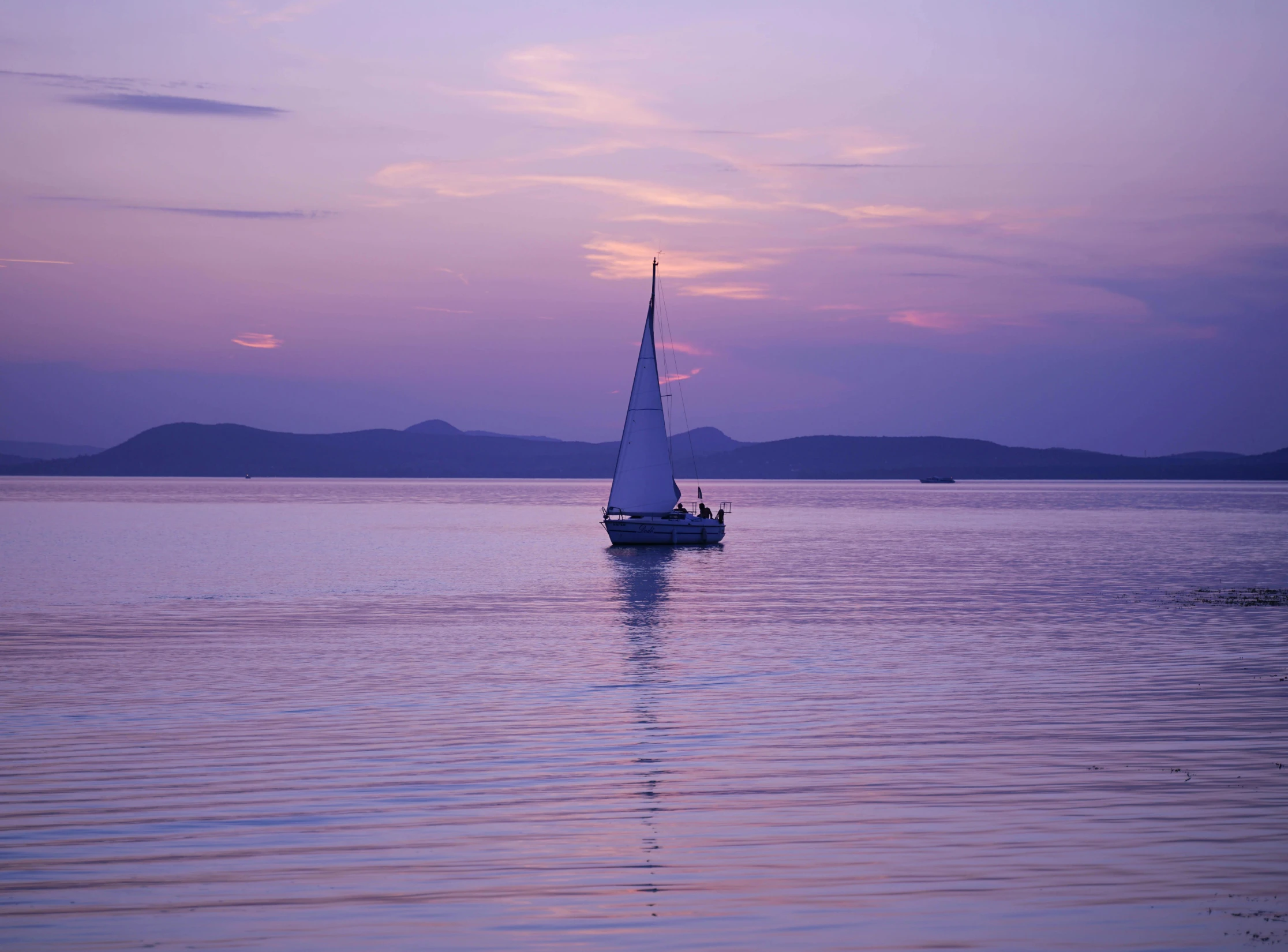 a sailboat sailing on the water during dusk