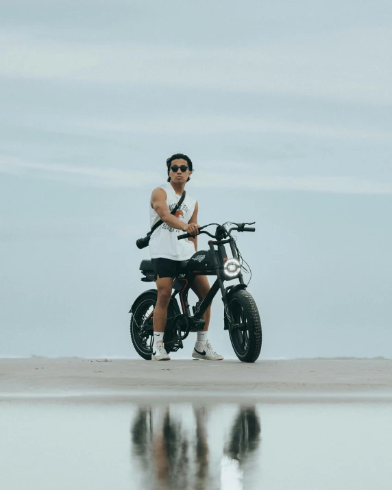 woman in sunglasses sitting on a bike at the beach