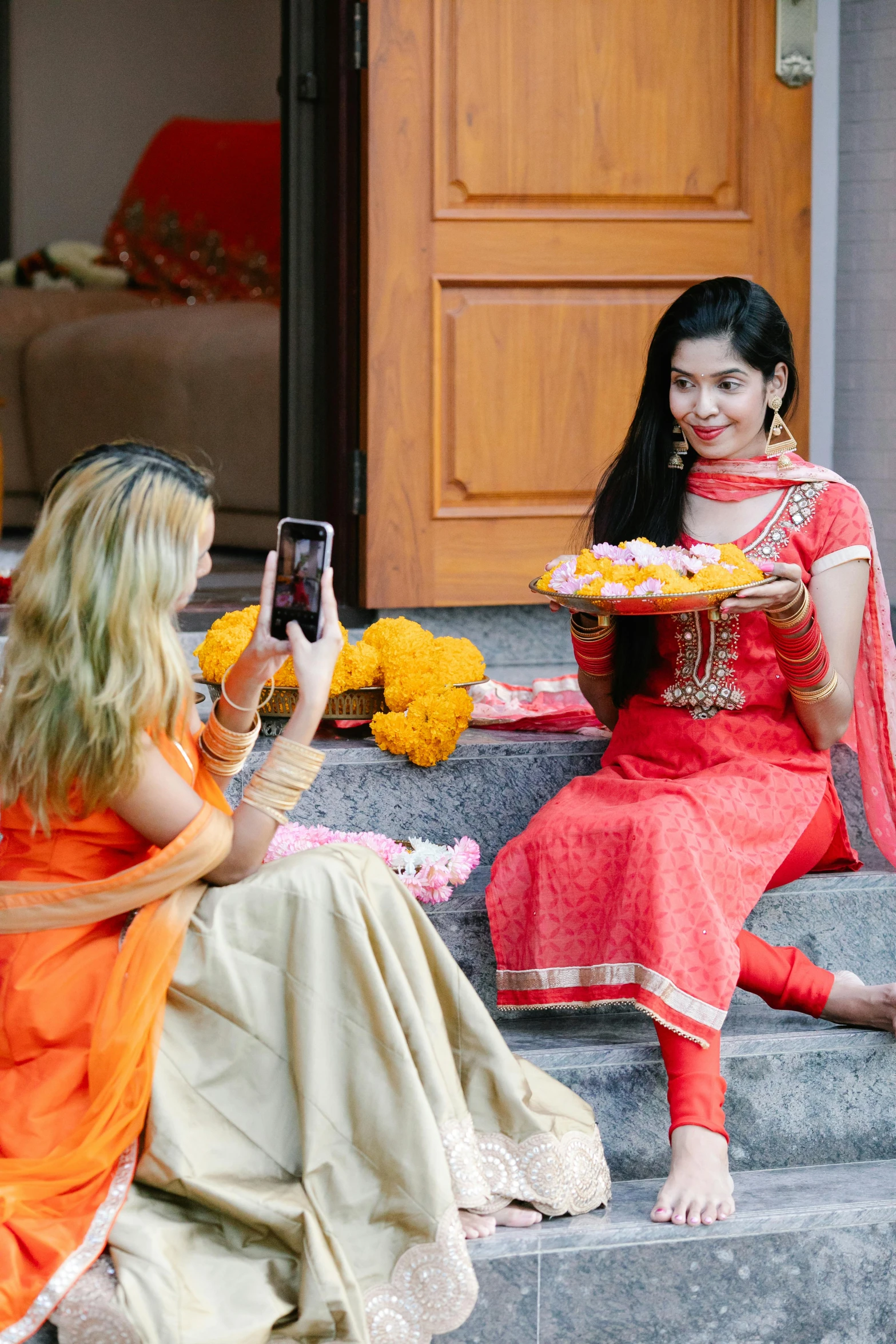 two ladies dressed in indian clothing sit on a step