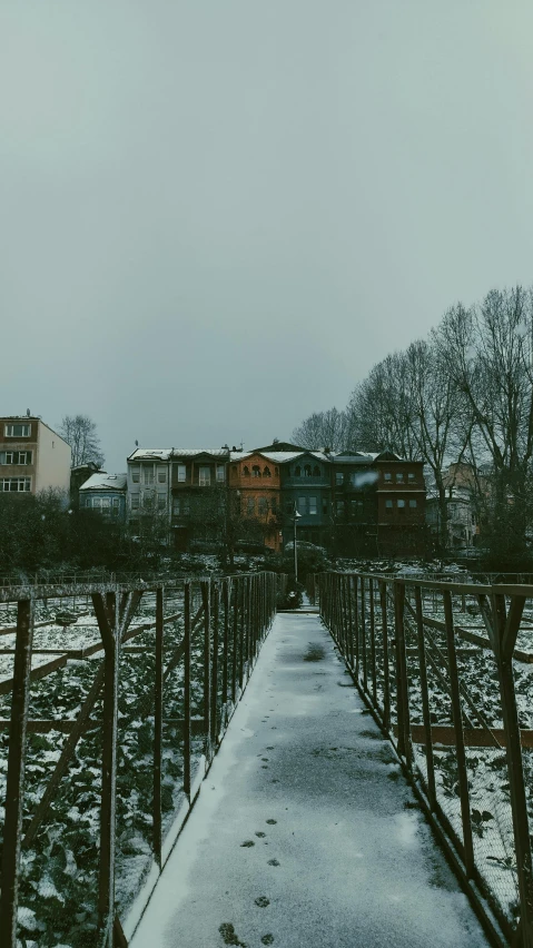 a walkway with snow on the ground and a city in the background