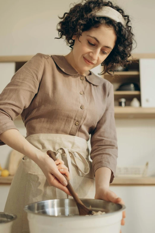 a woman in an apron is pouring liquid into a pot