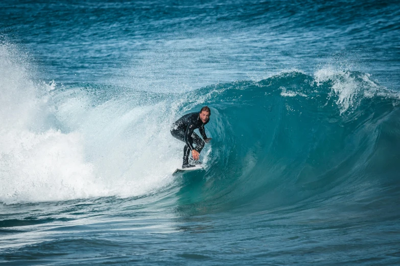 a man surfs on the ocean wave in black and blue