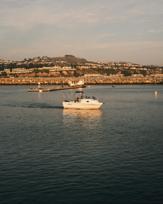 a white boat out on the water near a large city