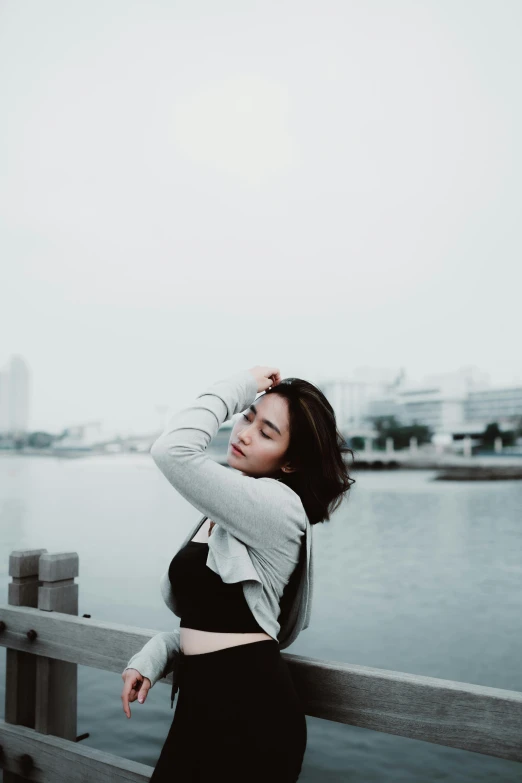 the girl is posing on the dock near the water