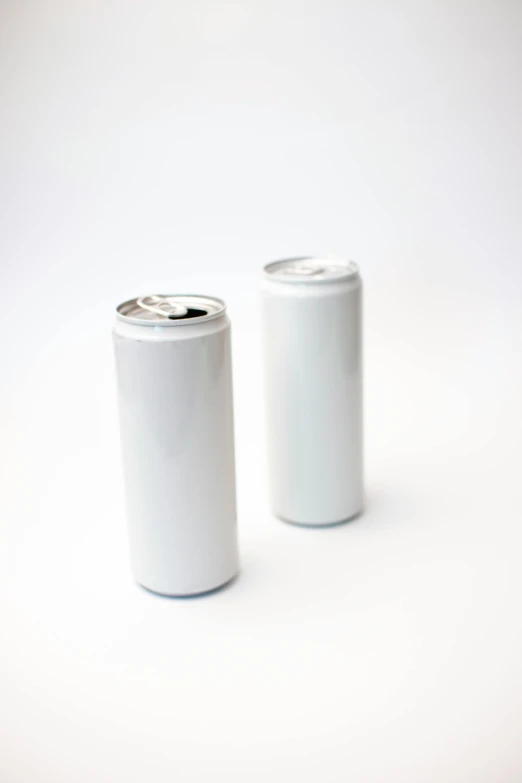 two white soda cans side by side on a white surface