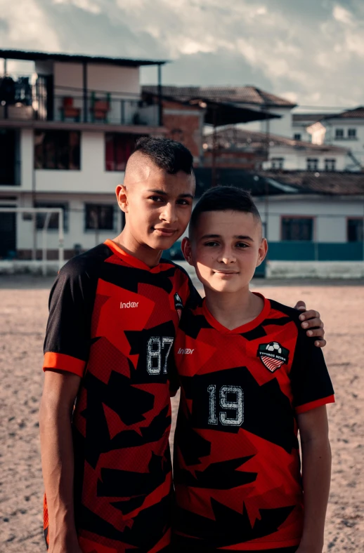 two boys in matching jerseys posing on the beach