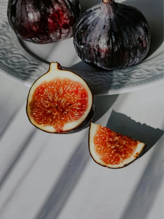 figs and oranges on white table, with shadow