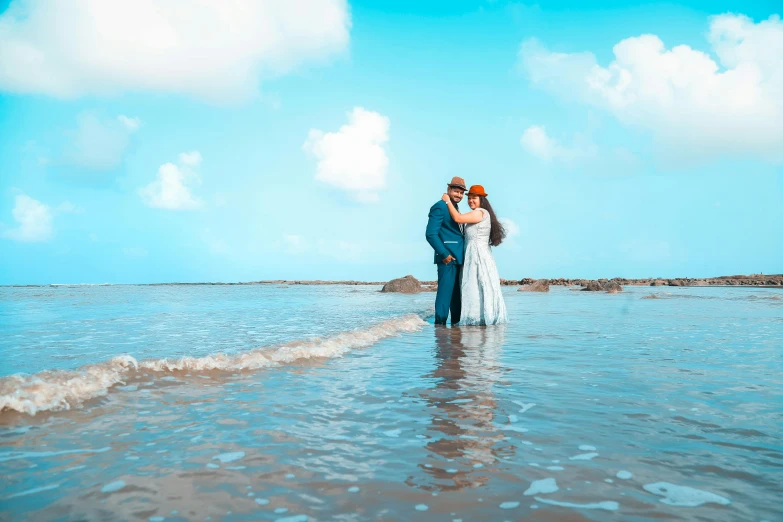 a man and woman standing in the ocean near a beach