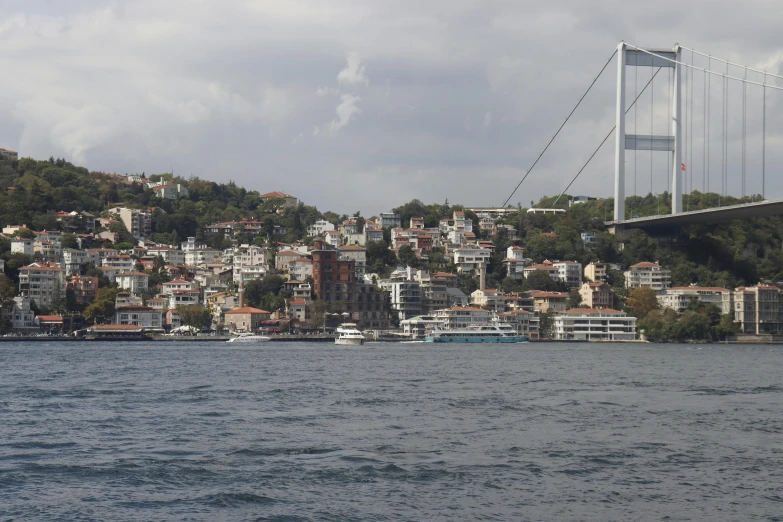 the bay is below a suspension bridge in the middle of the city