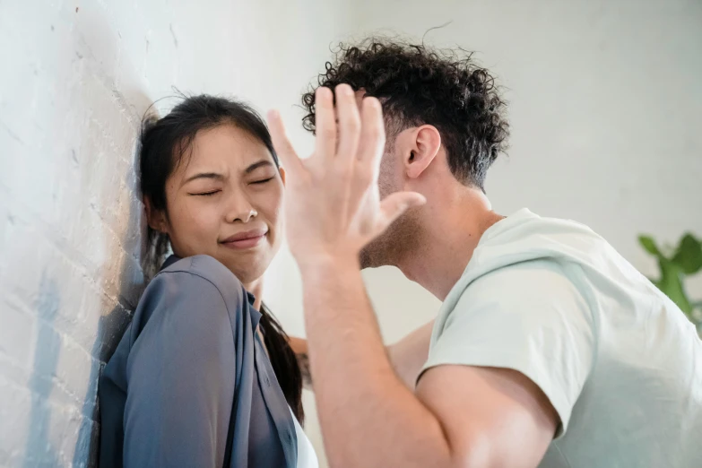 a man and woman standing together in front of a wall