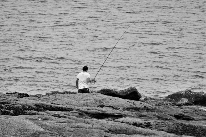 the man is fishing off the rocky shore