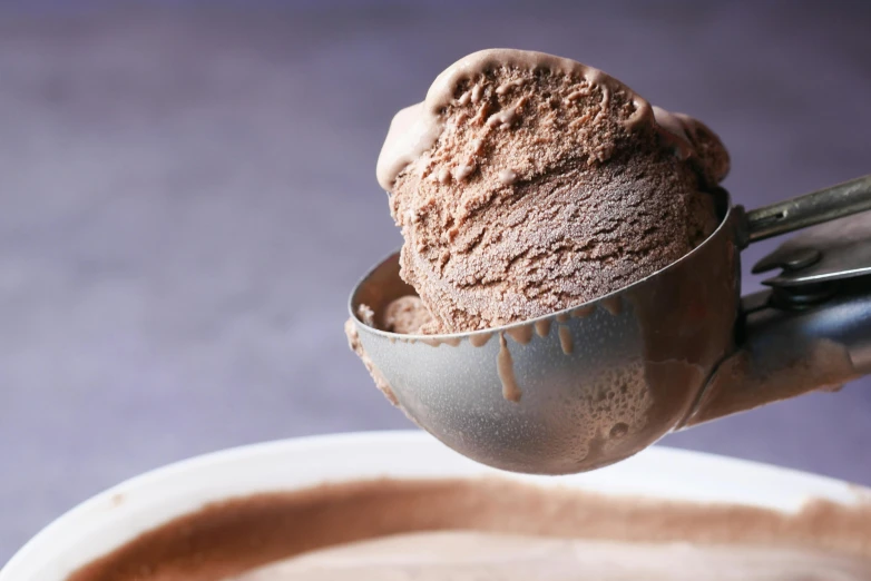 a chocolate ice cream scooping up into a bowl