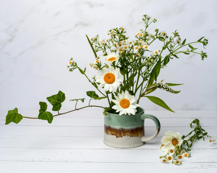 flowers are in a coffee cup with green leaves