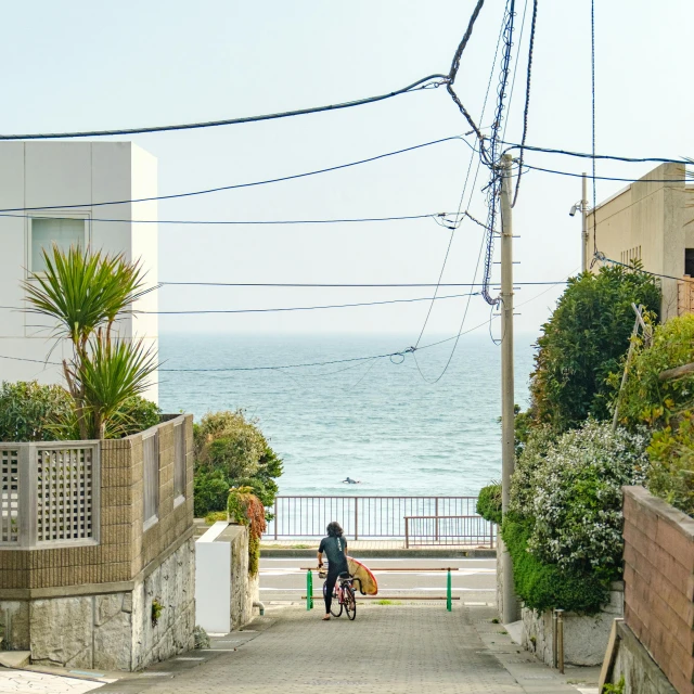 a man riding a bike down a small road next to the ocean