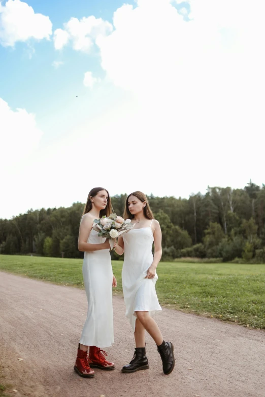 two girls in dresses on dirt path with flowers