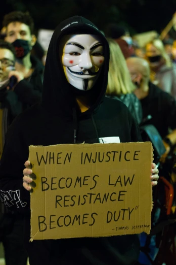 a person wearing a mask while holding a sign
