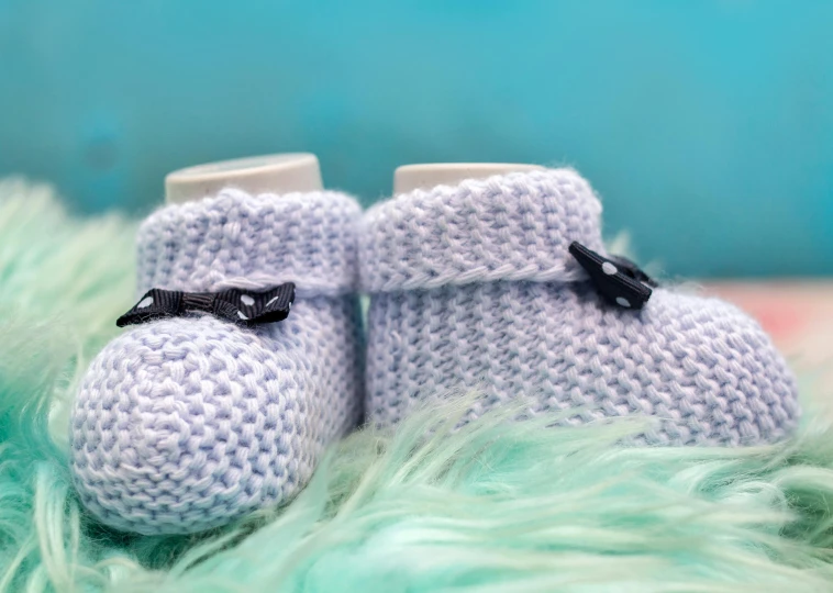 knitted boots with black bows sitting on top of green fur