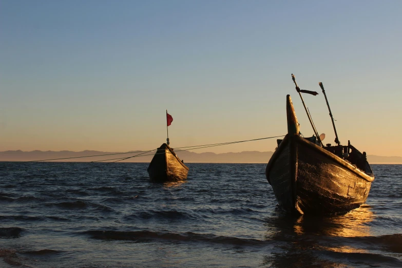 two boats floating on the water at dusk