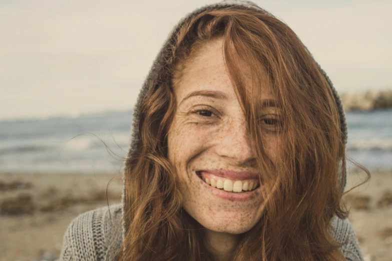 a woman smiling on the beach near a body of water