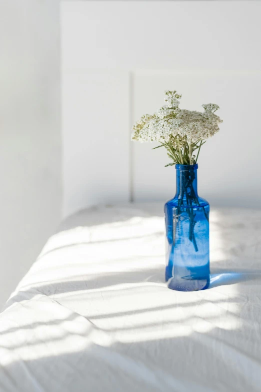 a blue glass vase with a few white flowers