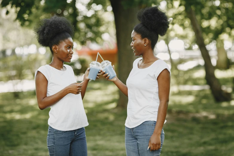 two young black women standing in a park while holding a book