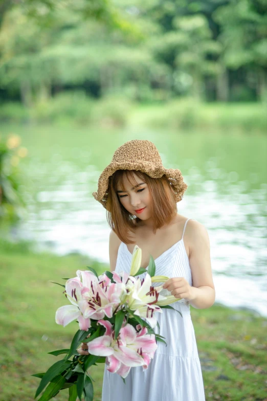 a woman holding flowers wearing a straw hat