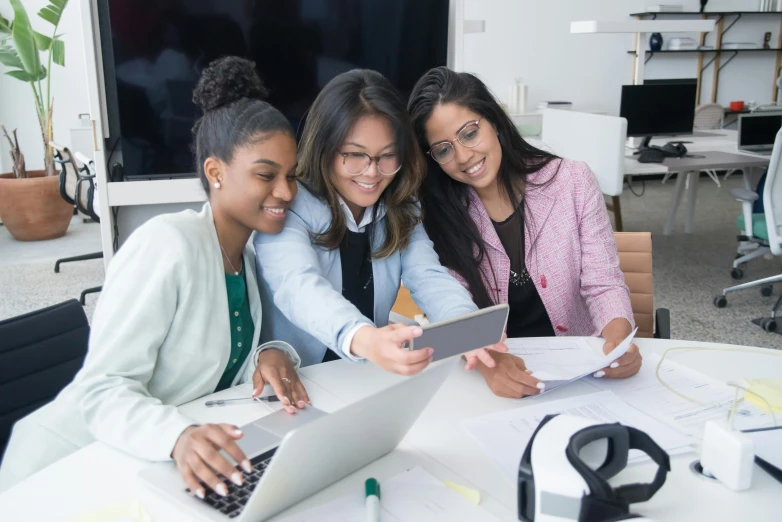 three women are around a table with papers