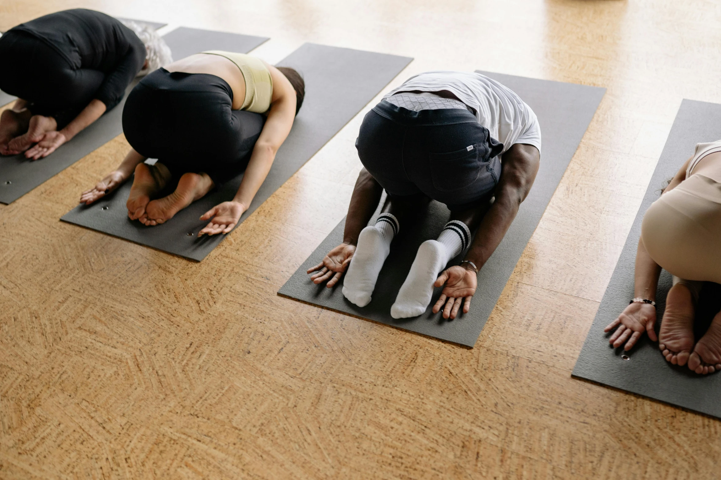 three men and one woman sitting on yoga mats with hands on their knees