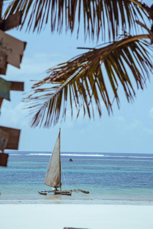 a small sailboat floating in the ocean near the beach