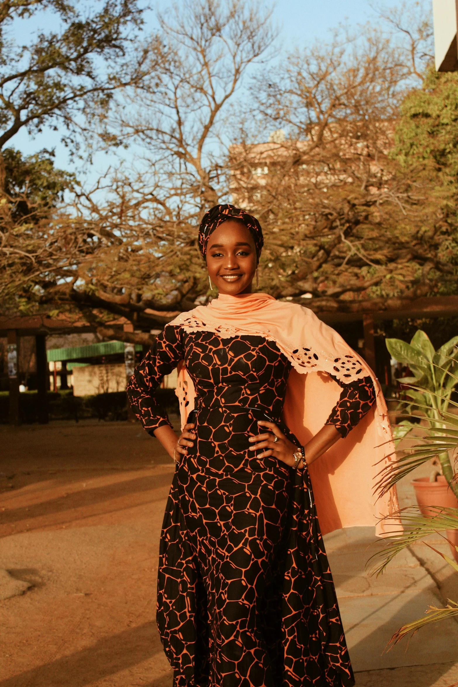 a smiling woman wearing a black dress with floral prints