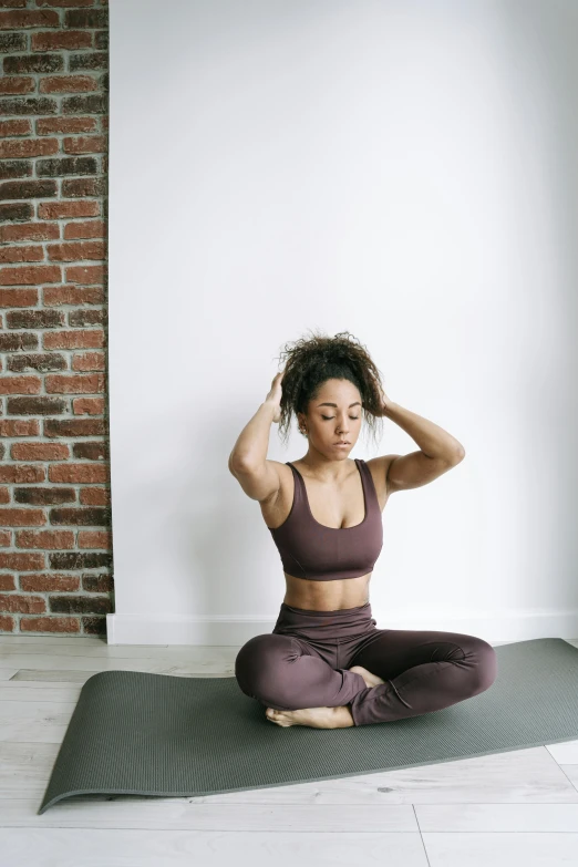 a woman in a dark  top meditates on a yoga mat