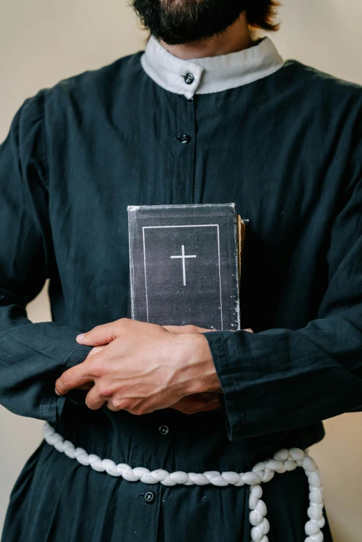 priest wearing the bible as a cross with beads around his pants