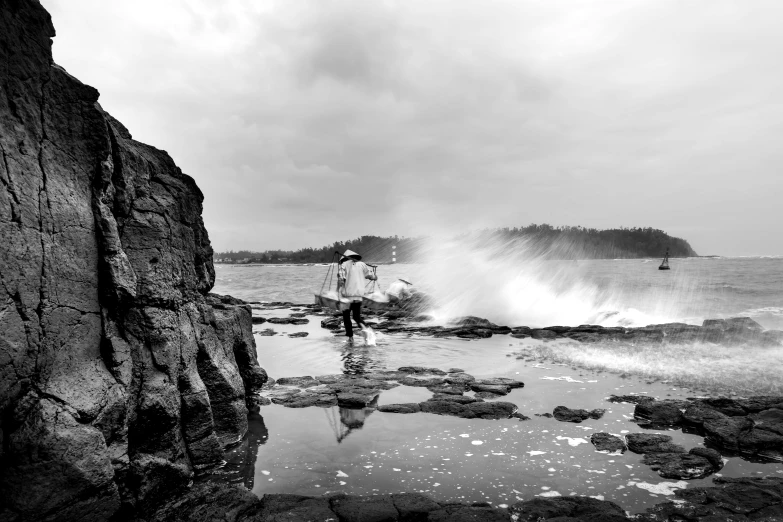 a man standing next to a crashing wave