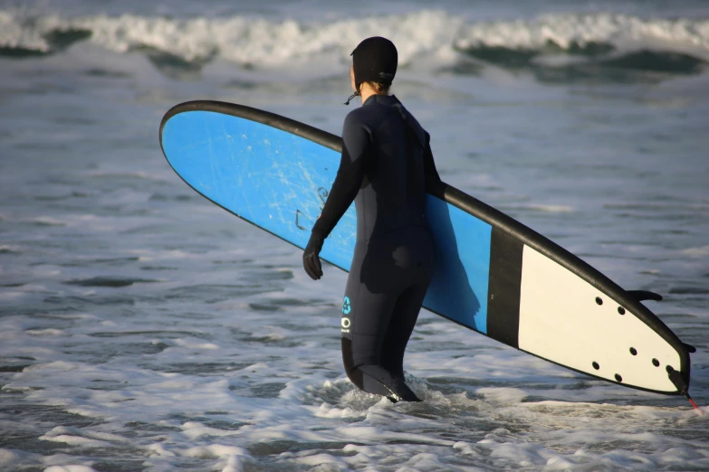 a surfer standing in the ocean, holding his board