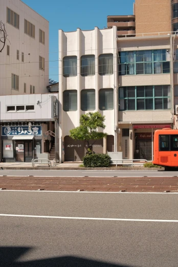 an orange bus driving past several white buildings