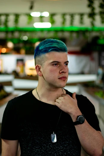 a young man is wearing blue hair while holding his watch