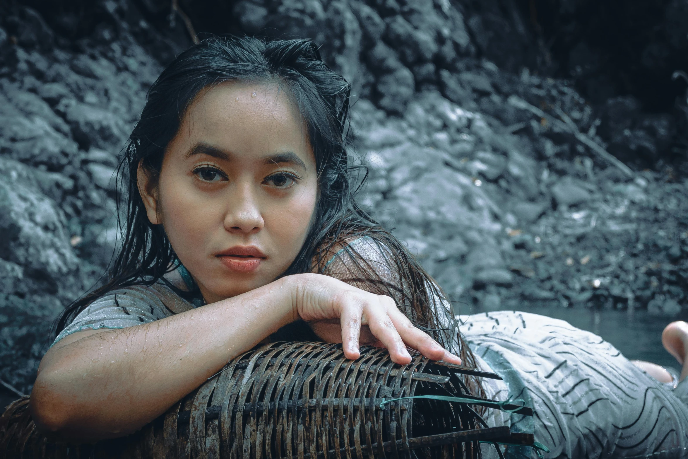 a woman that is sitting on a basket near some rocks