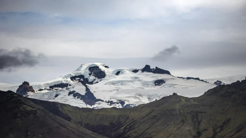 a very tall snow capped mountain with a bird perched on top of it