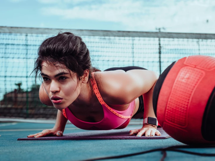 a woman on her belly is using a red ball