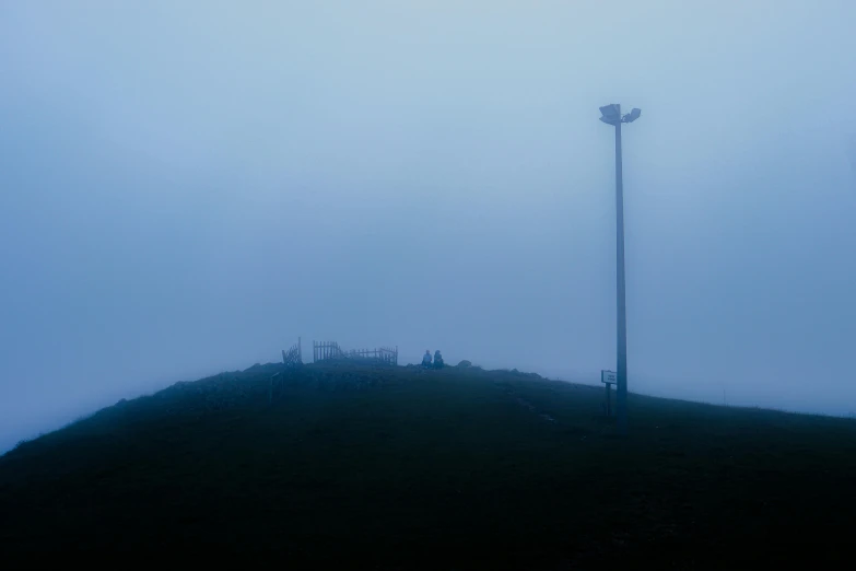 an empty street lamp on top of a hill in the fog