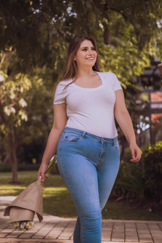 a woman in high waisted blue jeans carrying bags and smiling