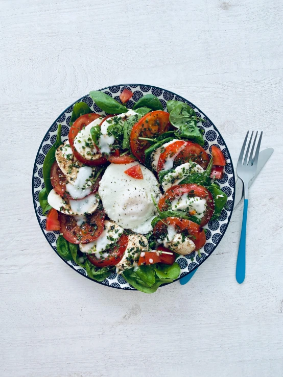 a colorful salad with lettuce and tomato in a black and white plate