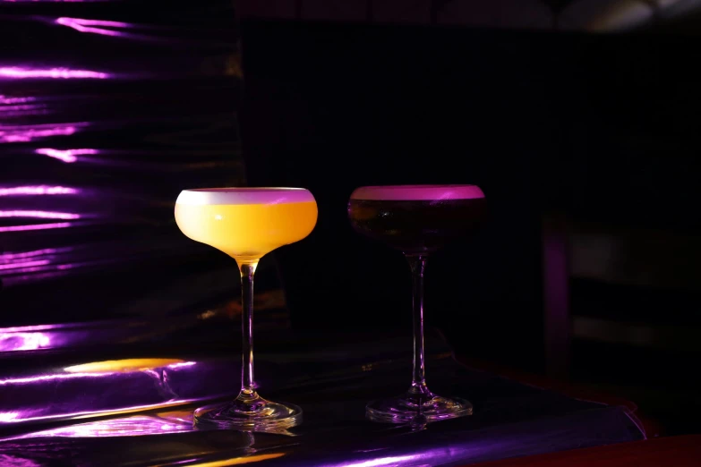 two different types of drinks on a purple bar